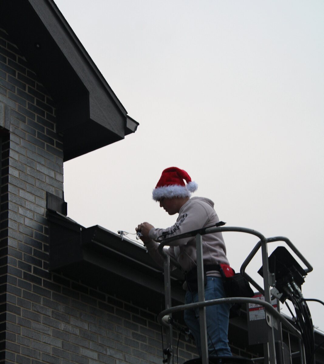 Twinkle Light Installations installer working from a lift near a roofline
